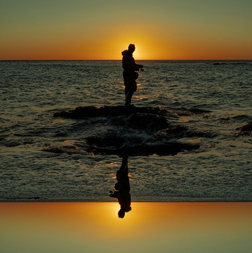 Fotomontaje de un pescador en atardecer generando efecto espejo